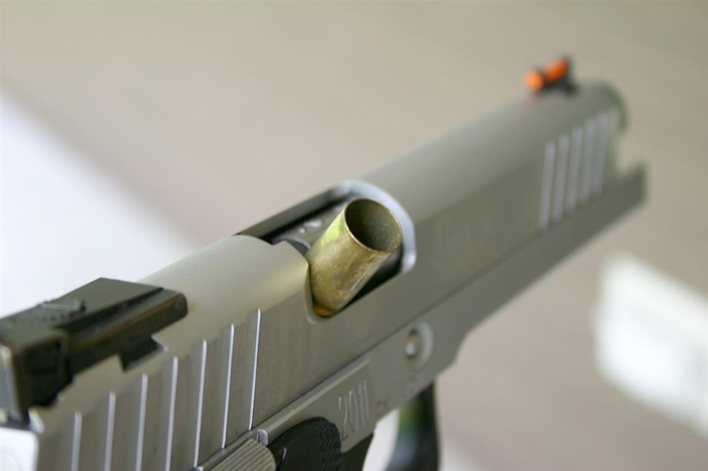 Semi automatic pistol with a cartridge case stovepiped in the ejection port for Jams and Malfunctions